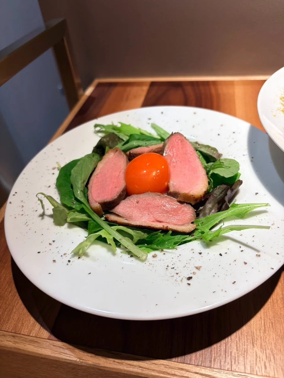 葉野菜の上に肉と赤い食材を盛り付けた一皿