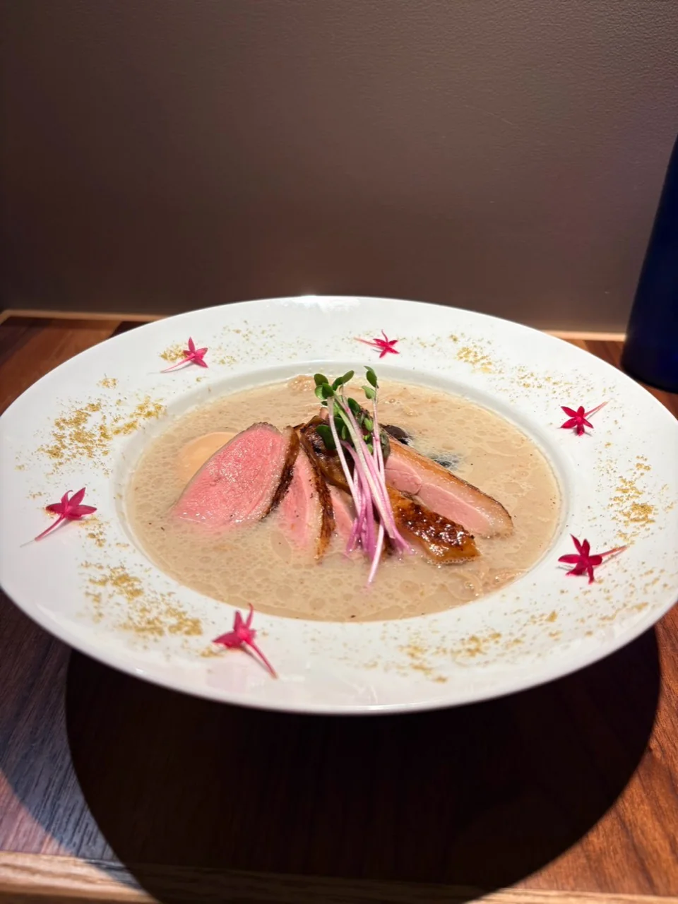 クリーミーなスープに肉と芽野菜を盛り付けた一皿